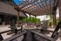 Inviting outdoor patio with elegant pergola, modern fire pit, and comfortable seating, perfect for relaxation and gatherings against a lush green backdrop.