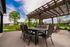 Charming patio with a modern pergola overlooking a serene neighborhood pond, perfect for outdoor dining and relaxation.