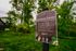 Inviting community garden sign nestled in lush greenery, highlighting communal space for planting flowers, vegetables, and herbs.