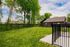Charming backyard view with lush green lawn, elegant black fencing, and scenic trees, perfect for relaxation and outdoor activities.