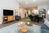 Modern open-plan living room with sleek hardwood floors, featuring a cozy seating area, stylish dining space, and elegant decor.