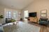 Inviting living room with stylish decor, featuring a large flat-screen TV on a wooden stand, cozy seating, and elegant glass doors opening to natural light.