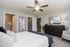 Elegant bedroom with contemporary decor, featuring a chic ceiling fan, cozy carpet, and sleek dark wood furniture.