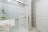 Modern bathroom with a sleek glass shower, elegant marble flooring, and convenient shelving.