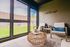 Charming sunlit enclosed patio with stylish wicker table, comfortable seating, and lush outdoor view.
