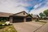 Charming modern townhouse with sleek double garage and manicured landscaping, set against a vibrant blue sky.