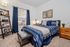 Inviting bedroom with stylish decor, featuring a comfortable bed, contemporary furniture, and a large window allowing natural light.