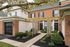 Charming brick townhouse with a stylish pergola and lush landscaping, enhancing curb appeal and elegance.