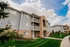Inviting apartment complex with charming balconies, brick accents, and lush green landscaping set against a bright blue sky.