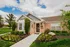 Charming brick home with manicured garden and lush greenery, set against a bright and cloudy sky.