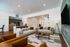 Contemporary living room with stylish sofas, modern kitchen in background, and chic decor, offering an inviting and open atmosphere.