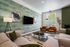 Elegant living room with stylish green walls, modern art, and comfortable seating around a sleek coffee table.