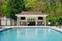 Inviting outdoor oasis featuring a sparkling pool, modern poolside cabana, and lush green surroundings.