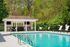 Inviting outdoor pool area with modern loungers, surrounded by lush greenery, perfect for relaxation and leisure.