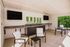 Modern outdoor lounge area with sleek seating, polished stone countertops, and dual wall-mounted TVs, perfect for entertaining and relaxation.