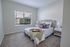Bright and inviting bedroom with a cozy bed, elegant decor, and abundant natural light from a large window, perfect for relaxation.