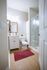 Modern bathroom with sleek vanity, elegant mirror, and a glass-enclosed shower, accented by a vibrant red rug.