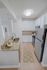 Modern kitchen with elegant granite countertops, stainless steel appliances, and sleek white cabinetry, highlighted by a stylish ceiling light.