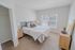 Bright, cozy bedroom featuring a sleek double bed, plush carpeting, and abundant natural light from large windows.