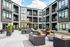 Modern apartment complex featuring stylish outdoor seating with lush gardens and vibrant decor, inviting a sense of luxury and comfort.