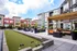Modern apartment courtyard featuring a bocce ball lawn, cozy seating area, and lush greenery under a blue sky.