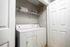 Modern laundry room featuring a sleek white washer and dryer set, with storage shelf above, optimizing space and functionality.