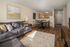 Inviting open-plan living area featuring a cozy gray sofa, elegant dining space, and a warm-toned kitchen with modern amenities.