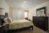 Inviting bedroom showcasing a chic design with a cozy bed, stylish wooden dresser, and ample natural light for a serene atmosphere.