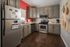 Inviting kitchen with modern stainless steel appliances, warm wooden flooring, and vibrant red accent wall.