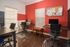 Inviting home office space with modern desks, ergonomic chairs, and vibrant red accent wall for a productive work environment.