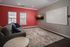 Modern living area with vibrant red accent wall, cozy gray sofa, and a sleek wall-mounted TV, ideal for relaxation and entertainment.
