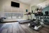 Modern apartment gym with state-of-the-art treadmill, elliptical machine, and large windows offering a serene pool view.
