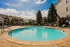 Bright and inviting apartment community pool area with clear blue skies and well-maintained landscaping.