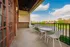 Inviting balcony with stylish white seating overlooking a serene lake and lush greenery under a bright blue sky.