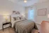 Elegant bedroom with modern decor, featuring a plush bed, chic artwork, and soft natural light from a large window.