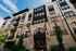 Modern brick apartment building with balconies, adorned with American and state flags, under a clear blue sky.