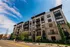 Contemporary urban apartment building with stylish brick facade and large windows under a bright blue sky.