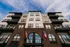 Modern apartment building facade with stylish balconies and elegant brickwork under a blue sky.