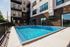 Luxurious apartment complex featuring a sparkling swimming pool surrounded by modern architecture and cozy seating area.