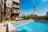 Chic urban patio featuring a sparkling pool, modern lounge chairs, and vibrant red umbrellas against a stylish apartment backdrop.