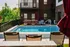 Inviting apartment pool area with sun loungers, vibrant greenery, and modern seating under patio umbrellas.