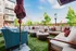 Chic outdoor seating area with plush cushions, surrounded by greenery and modern apartment buildings, perfect for leisurely gatherings.