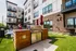 Modern apartment building with stylish outdoor grilling area, surrounded by lush greenery and contemporary design features.