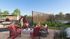 Vibrant outdoor patio featuring a cozy fire pit, stylish red chairs, lush greenery, and a hammock showcasing a relaxing atmosphere.