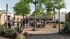 Vibrant outdoor community space featuring a modern food truck, string lights, and live music, surrounded by lush greenery and socializing guests.