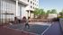 Modern apartment complex featuring vibrant outdoor pickleball court with players enjoying a sunny day, complemented by stylish urban architecture and lush greenery.