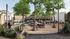Modern outdoor communal space featuring lush greenery, string lights, and people enjoying activities and dining at picnic tables.