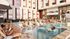 Vibrant apartment complex showcasing a luxurious swimming pool with loungers, socializing residents, and a modern outdoor lounge area.
