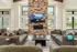 Inviting living room with plush seating, stone fireplace, and modern decor, adorned with large windows for abundant natural light.