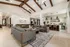 Luxurious living area with vaulted ceilings, modern sofas, elegant chandelier, and a stylish kitchen bar in an upscale apartment.